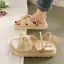 White cream ribbed fabric flatform bow sandals with beige crepe sole, shown worn on foot and as flat lay, angled view.