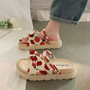Cream and red strawberry print flatform sandals with bow detail and chunky crepe sole, worn with rolled denim, angled view.