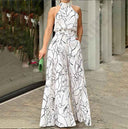 White halter-neck jumpsuit with black abstract print, front view on a city street.