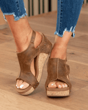 Coffee tan suede-look cork platform wedge sandals with cutout upper and stud trim, front angled view on wooden floor.