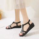 Black embellished flatform sandals with rhinestone cage straps, open-toe T-bar style on neutral background, angled front view.