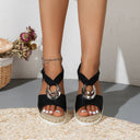 Black espadrille wedge sandals with cross ankle strap and silver ring hardware on rope-wrapped jute sole, front view on model.