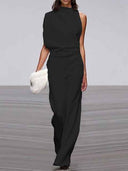 Black sleeveless crew neck jumpsuit, front view, with a white furry clutch.