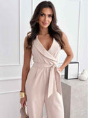 Beige sleeveless jumpsuit with wrap-style top, tie waist, and wide legs, angled view.