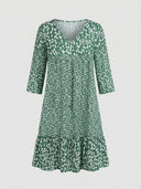 Green mini dress with white floral print, V-neck, and tiered ruffle hem, front view.