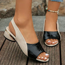 Two-tone low wedge sandal in black croc-effect front strap and white smooth slingback, peep-toe silhouette, angled view.