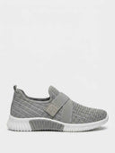 Grey slip-on knit trainer with sparkle-studded upper, wide elasticated strap, and ribbed white sole — side view.