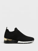 Black slip-on knit trainer with gold heel accent, white midsole stripe, and non-slip rubber sole, side view.