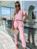 Pink jumpsuit with V-neck, short sleeves, and tie waist, front view.