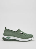 Green knit slip-on trainer with cut-out strap and white cushioned midsole, side view on light background.