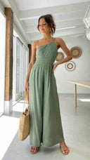 Green asymmetrical strapless jumpsuit with high waistline, full-body front view.