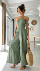 Sage green asymmetrical strapless jumpsuit with high waist and wide legs, front view in a bright room.