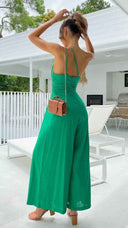 Green asymmetrical strapless high-waist jumpsuit with brown bag, back view.