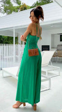 Green asymmetrical strapless jumpsuit with high waistline, shown from the back against a white patio background.