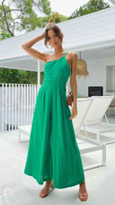 Green asymmetrical strapless jumpsuit with high waistline, worn by a model, front view on a patio.