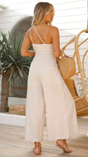 Beige asymmetrical strapless jumpsuit with high waist, shown from the back.