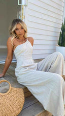 Light beige asymmetrical strapless jumpsuit with high waistline, angled view.