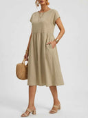 Amelia cap sleeve empire waist midi sundress in khaki, angled front view styled with rattan bag and gold jewellery.