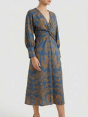 Amelia floral A-line midi dress in blue with amber botanical print, deep V-neck, twisted-knot waist and full-length bishop sleeves, angled front view.