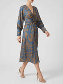 Amelia floral midi dress in blue with amber botanical print, A-line skirt and twisted waist, three-quarter front view showing bishop sleeve cuff detail.