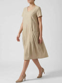 Amelia V-neck cap sleeve midi dress in warm sandy khaki, relaxed A-line with large front patch pockets, angled front view on white background.