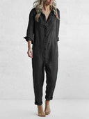 Dark gray long sleeve jumpsuit with button closure, front pockets, and rolled cuffs, front view.