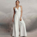 White backless V-neck spaghetti strap jumpsuit with relaxed legs, front view on a cloudy background.