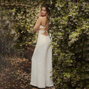 White backless jumpsuit with spaghetti straps and relaxed legs, angled back view.