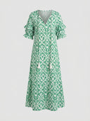 Beatrice Floral V-Neck Maxi Summer Dress in Green with ikat-style floral print, tassel tie neckline and ruffled short sleeves, front view.