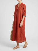 Beatrice linen-look maxi dress in rust terracotta, angled front view highlighting side pockets and slub-woven linen-look texture.