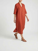 Beatrice linen-look maxi dress in rust terracotta worn on model, angled view showing full ankle-grazing maxi length and relaxed boxy fit.