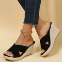 Black cross-strap wedge mule sandals with woven cream platform sole, styled with dark jeans and gold ankle bracelet.