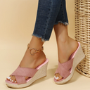 Pink cross-strap wedge mule sandals with woven espadrille platform sole, angled side view.