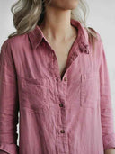 Pink linen-cotton jumpsuit with two chest pockets and brown buttons, angled close-up.