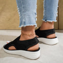 Black knit slip-on flatform sandals with open toe and white platform sole, angled front view on neutral background.