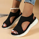 Black knit slip-on flatform sandals showing curved lateral cut-out detail and white cushioned sole, angled front view.