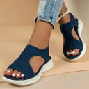 Dark blue knit slip-on flatform sandals with curved cut-out upper and white cushioned sole, angled front view.