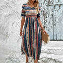 Calypso Striped Short Sleeve Midi Dress in navy, terracotta, and cream vertical stripes with empire waist and gathered skirt, front view on model outdoors.