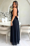Black maxi dress with open back and tie detail, angled back view.