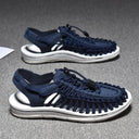 Navy blue woven sandals with white sole and lace-up closure, angled side view showing pair.