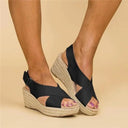 Black espadrille platform wedge sandals with crisscross straps and braided jute wedge heel, angled front view.