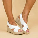 White espadrille wedge sandals with crossover straps and jute rope sole, worn on feet against a neutral background.