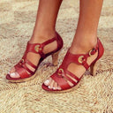 Burgundy leather high heel sandals with gold buckle accents and cork heel, angled front view.