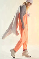 Peach jumpsuit with side pockets, worn with gray long-sleeve top, side view.