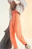 Orange V-neck jumpsuit with large pockets, worn with a white fleece jacket, angled view.