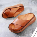 Brown cross-strap platform sandals with cushioned sole, angled top view on grey background.