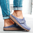 Blue suede closed-toe platform mules with adjustable buckle strap and cork flatform sole, worn on foot from side angle.