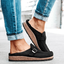 Black closed-toe platform mules with cork flatform sole and adjustable buckle strap, side view.