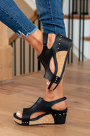 Black platform wedge sandals with cork sole and silver stud detail, side view showing wedge height and ankle strap.
