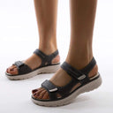 Coral orthotic sandals with black straps and cushioned sole, angled front view on feet.